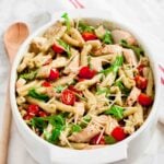 Overhead shot of chicken pesto pasta salad with sliced cherry tomatoes.