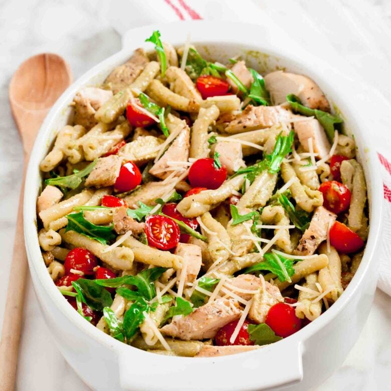 Overhead shot of chicken pesto pasta salad with sliced cherry tomatoes.