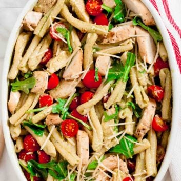 Overhead shot of chicken pesto pasta salad with sliced cherry tomatoes.