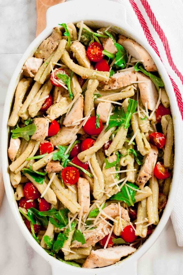 Overhead shot of chicken pesto pasta salad with sliced cherry tomatoes.