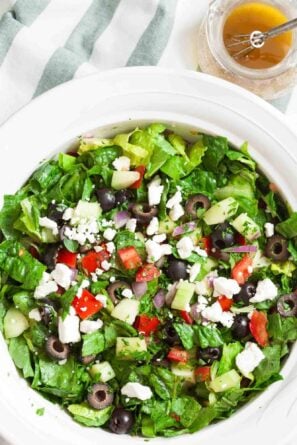 Overhead shot of chopped Greek salad with fresh romaine lettuce. Garnished with crumbled feta cheese.