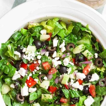 Overhead shot of chopped Greek salad with fresh romaine lettuce. Garnished with crumbled feta cheese.