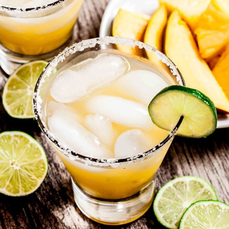 Overhead shot of mango margarita with lime and mango slices around it. 