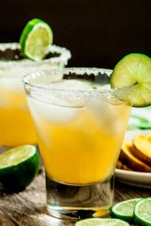 Closeup shot of a mango margarita glass with a lime wedge.