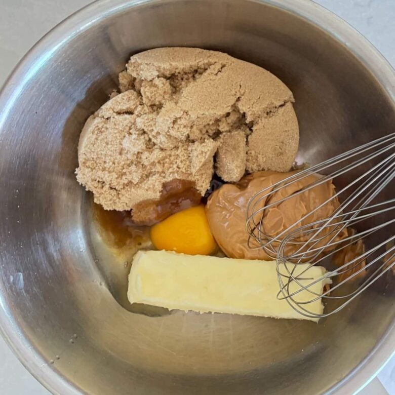 Brown sugar, eggs, and butter in a large metal bowl.