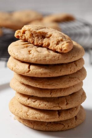 A stack of chewy peanut butter cookies with the top one half eaten.