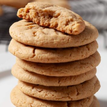 A stack of chewy peanut butter cookies with the top one half eaten.
