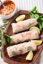 Three freshly made Vietnamese spring rolls with lime wedges on the side.