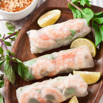 Three freshly made Vietnamese spring rolls with lime wedges on the side.