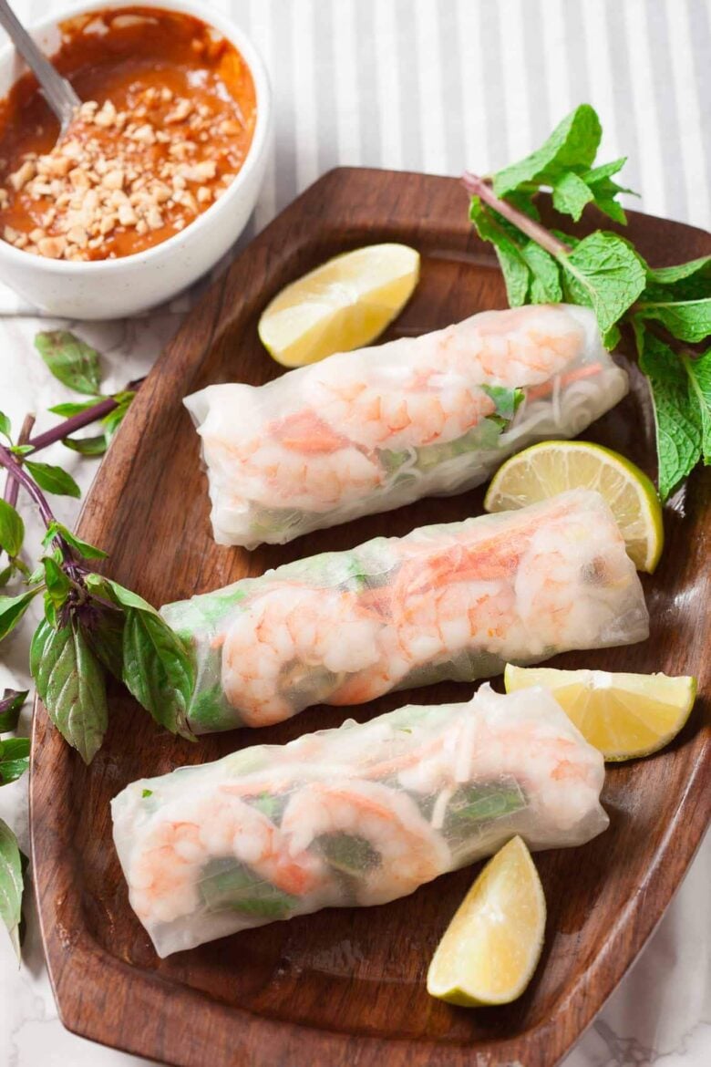 Three freshly made Vietnamese spring rolls with lime wedges on the side.