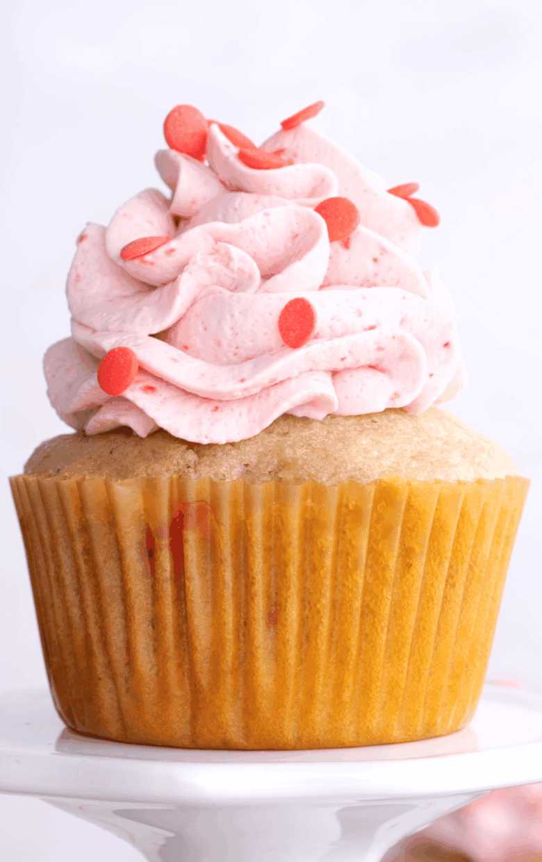 Closeup shot of strawberry cupcake with whipped cream frosting.