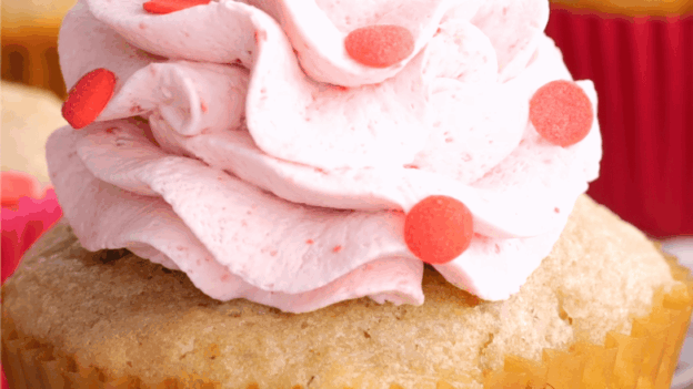 Closeup shot of strawberry cupcake with whipped cream frosting.