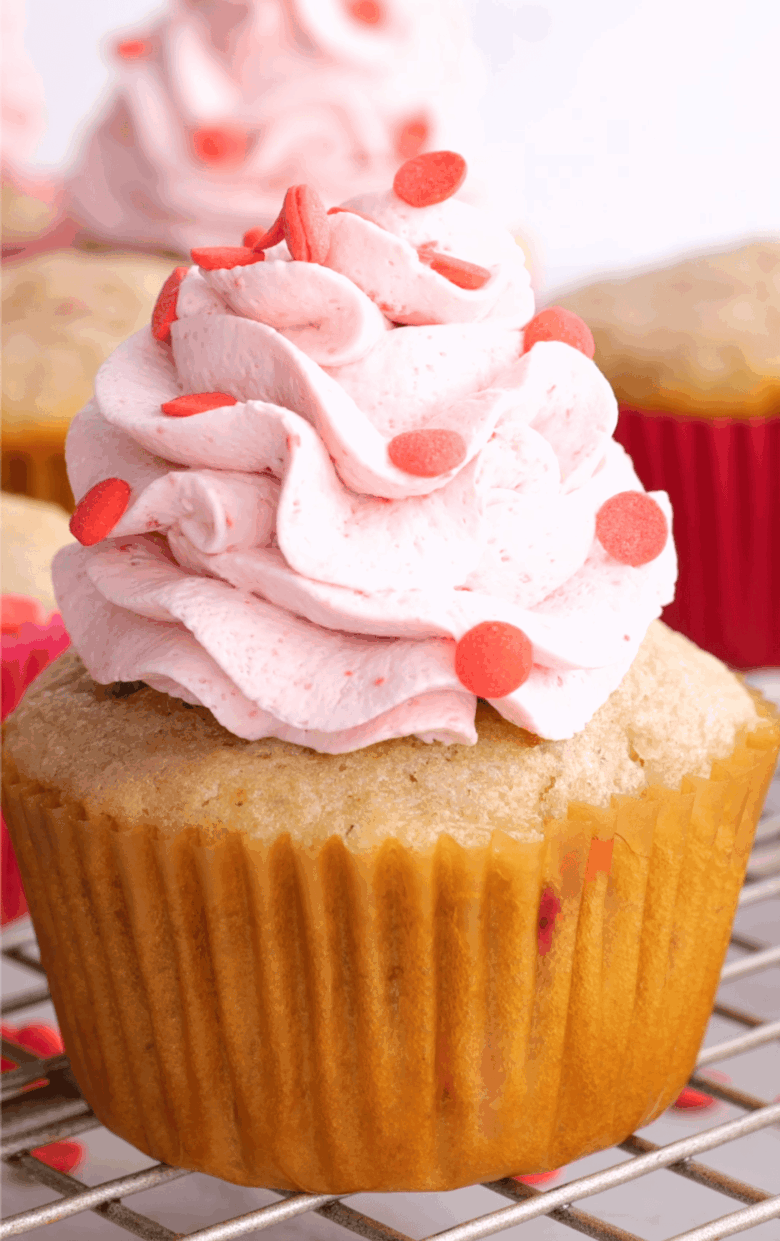 Closeup shot of strawberry cupcake with whipped cream frosting.