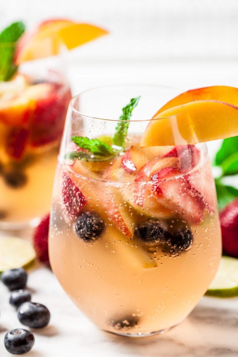 Summer sangria with wine, soda, peaches, berries, and mint.