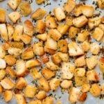 A sheet filled with golden brown, crispy garlic croutons garnished with chopped herbs.