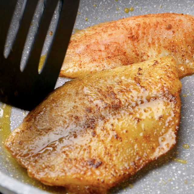 Seasoning being sprinkled on tilapia fillets to make pan seared tilapia.