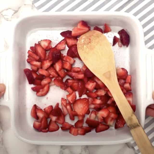 Strawberries being combined with sugar to macerate to make frosé recipe.