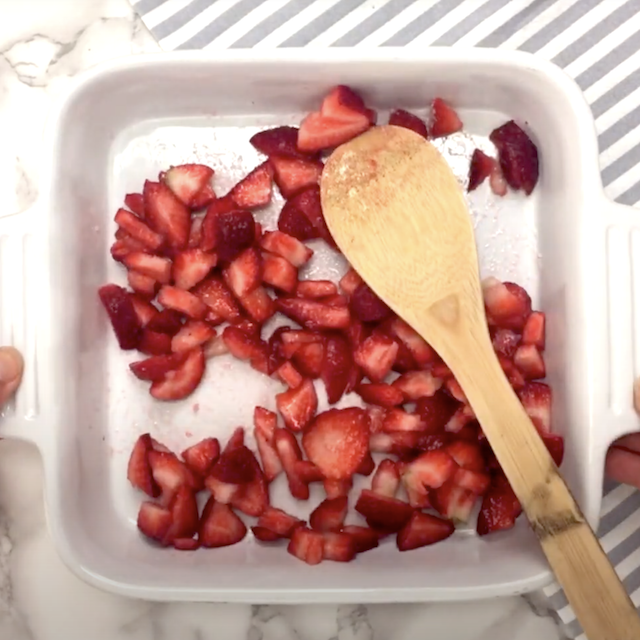 Strawberries being combined with sugar to macerate to make frosé recipe.