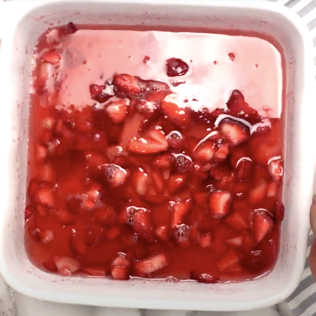 Rosé added to macerated strawberries, ready to be frozen to make frosé recipe.