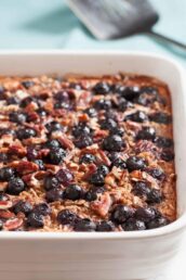 Gluten-free Baked Blueberry Oatmeal in a white dish, topped with blueberries and chopped pecans, makes a healthy breakfast.