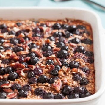 Gluten-free Baked Blueberry Oatmeal in a white dish, topped with blueberries and chopped pecans, makes a healthy breakfast.