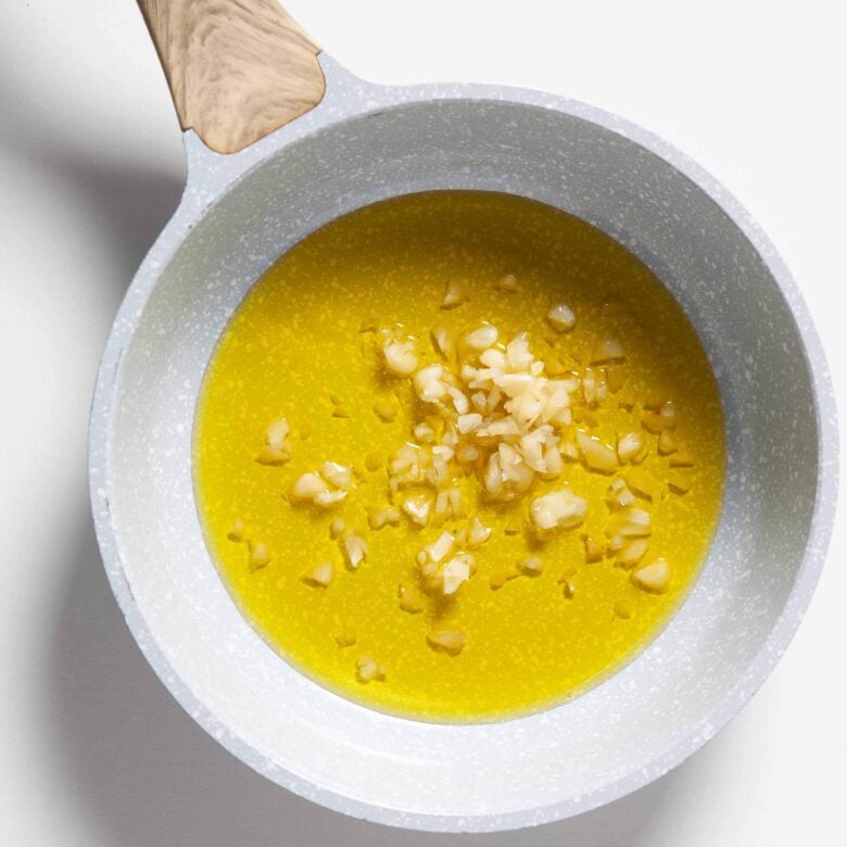 Oil and chopped garlic in a pan to infuse the oil to make garlic croutons.