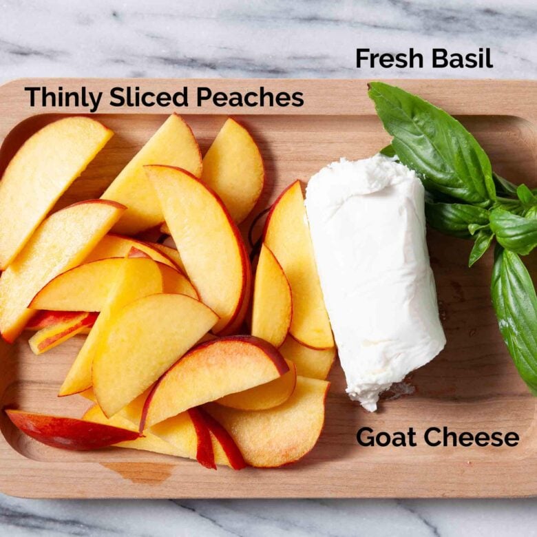 Ingredients to make peach crostini such as fresh peach, basil and goat cheese.
