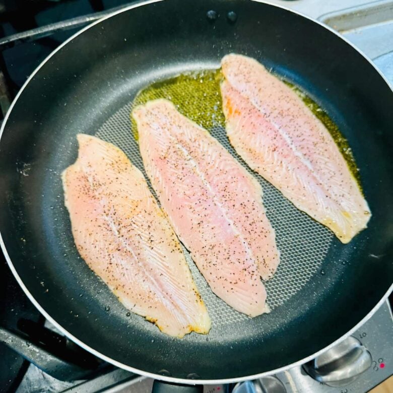 Seasoned rockfish fillets being seared in a pan.