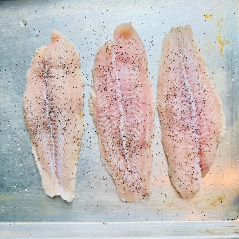 Rockfish fillets being seasoned to make pan seared rockfish.
