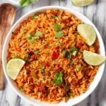 Overhead shot of a bowl of Instant Pot Mexican Rice, garnished with freshly chopped cilantro and lime wedges.