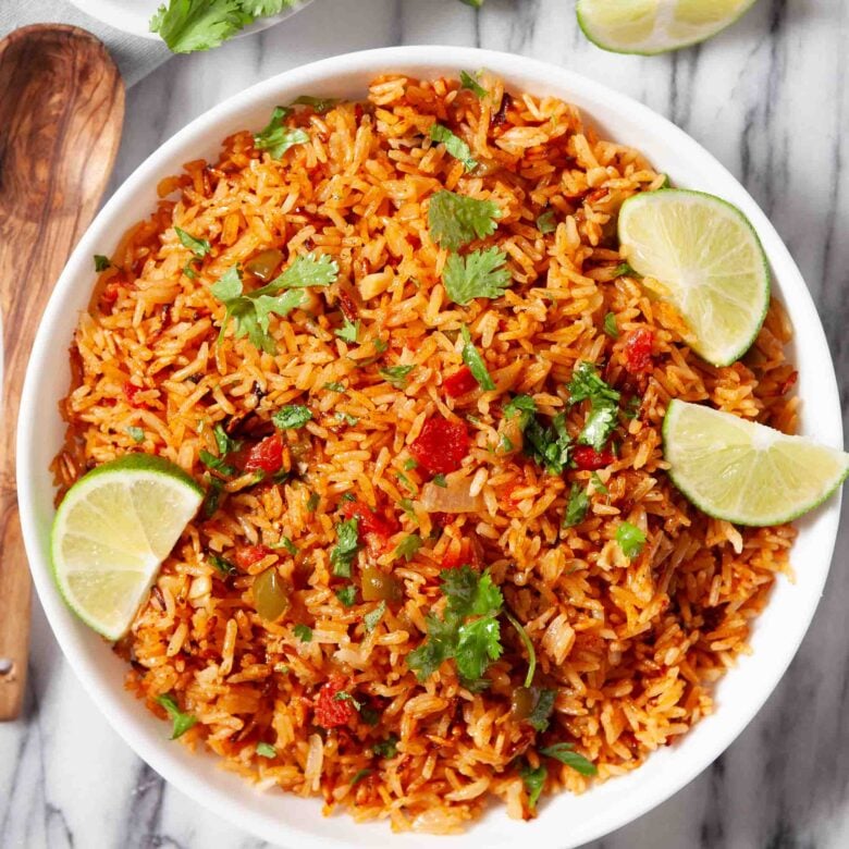 Overhead shot of a bowl of Instant Pot Mexican Rice, garnished with freshly chopped cilantro and lime wedges.