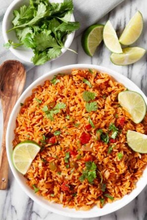 Overhead shot of a bowl of Instant Pot Mexican Rice, garnished with freshly chopped cilantro and lime wedges.