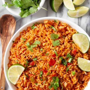 Overhead shot of a bowl of Instant Pot Mexican Rice, garnished with freshly chopped cilantro and lime wedges.