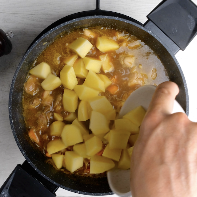 Soaked potatoes being added to Japanese chicken curry.