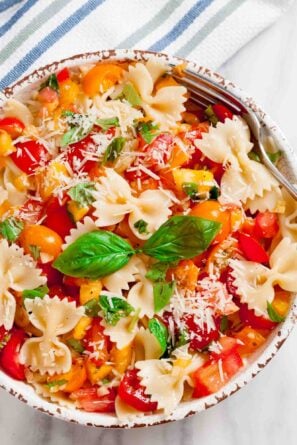 Overhead shot of a bowl with fresh tomato basil pasta with fresh basil leaves and visible tomato chunks.