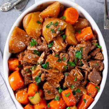 Overhead shot of Instant pot roast beef in a serving dish on a grey surface.