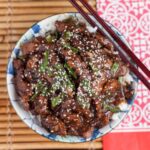 Overhead shot of a bowl with homemade Mongolian beef recipe with sesame seeds on top.
