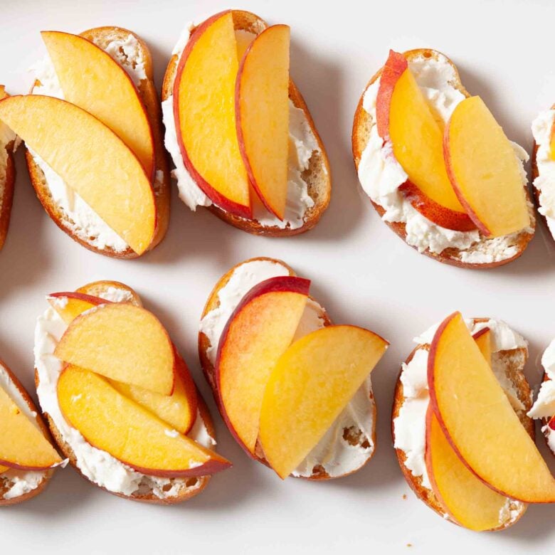 Goat cheese and peach slices layered on top of baguette to make peach crostini.