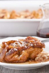 A slice of make-ahead apple french toast casserole on a white plate, with a fork.