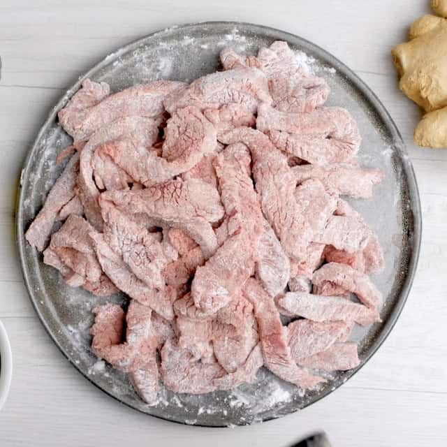 Cornstarch coated beef strips left to rest to make mongolian beef at home.