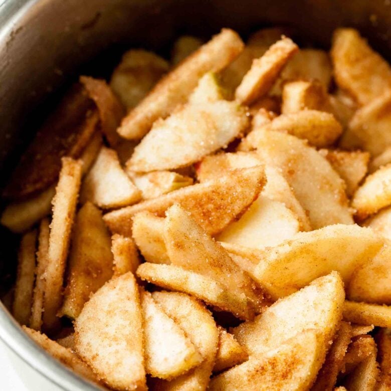 Sliced apples tossed with cinnamon sugar to make apple pie bars at home.