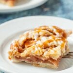 Closeup shot of a apple pie bar, drizzled with homemade salted caramel sauce.