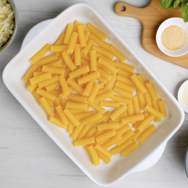 Uncooked rigatoni in an even layer in a casserole.