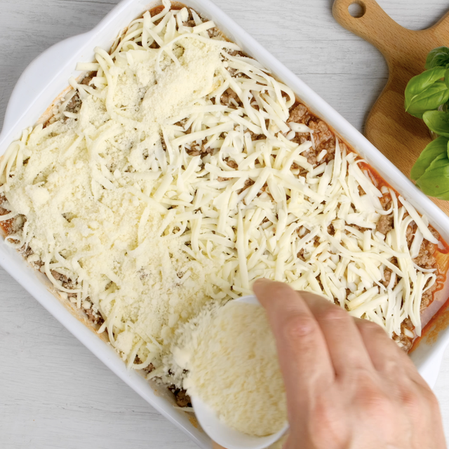 Cheese being added to baked rigatoni casserole being baking.