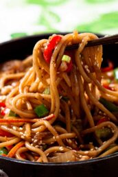 Closeup shot of lo mein noodles being held by chopsticks.