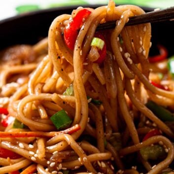 Closeup shot of lo mein noodles being held by chopsticks.
