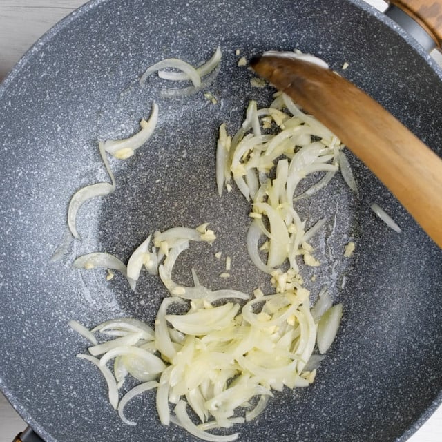 Onions and garlic being sautéed in a pan.