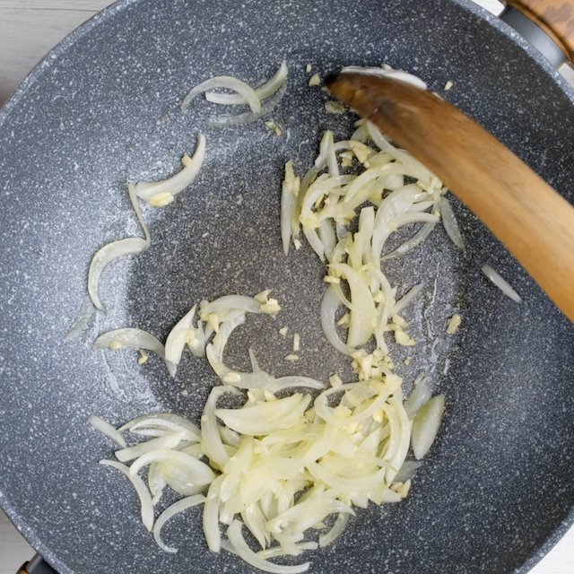 Onions and garlic being sautéed in a pan.