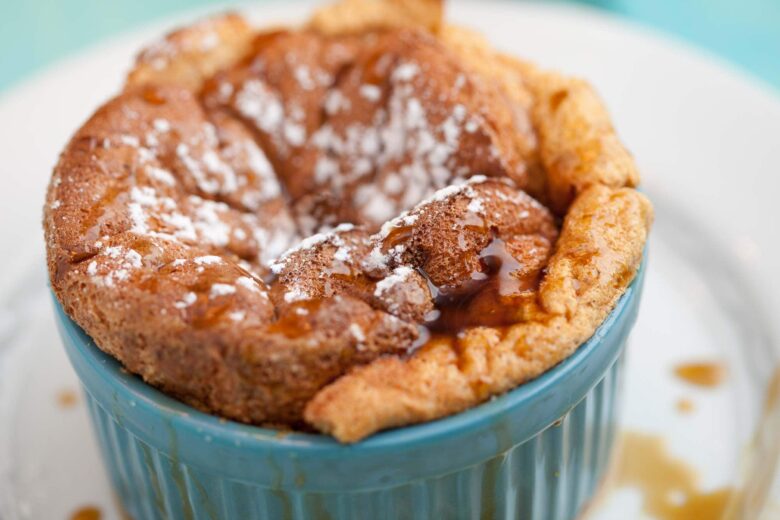 Overhead shot of freshly baked pumpkin soufflé in a blue ramekin.