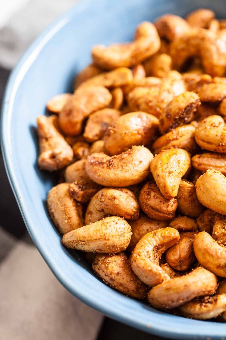 A close-up of roasted cashews in a blue bowl, making the perfect party snack.
